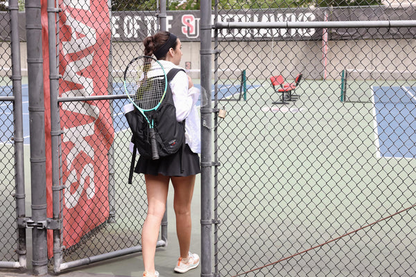 A person carrying a Smart Alec 2.0 with a tennis racquet attached to the front.